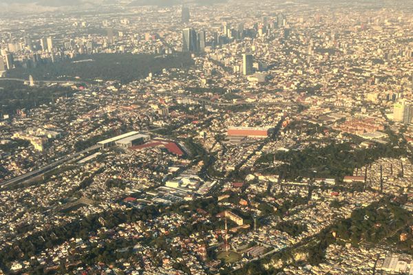 Anflug im Sonnenuntergang auf das Häusermeer von Mexiko City mit dem Bosque de Chapultepec.