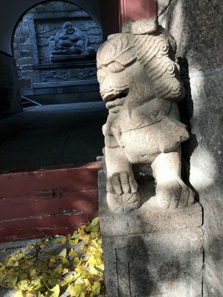 Ein Löwe bewacht den Eingang. Lachender Buddha im Hintergrund. Ein Löwe bewacht den Eingang. Lachender Buddha im Hintergrund.