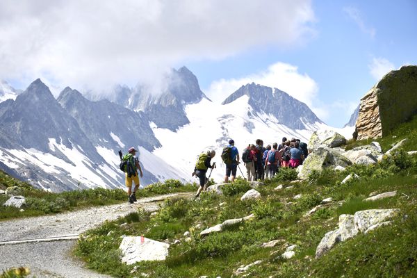 Wandergruppe vor schneebedeckten Bergen zum Oberaarsee. Wandergruppe vor schneebedeckten Bergen zum Oberaarsee.
